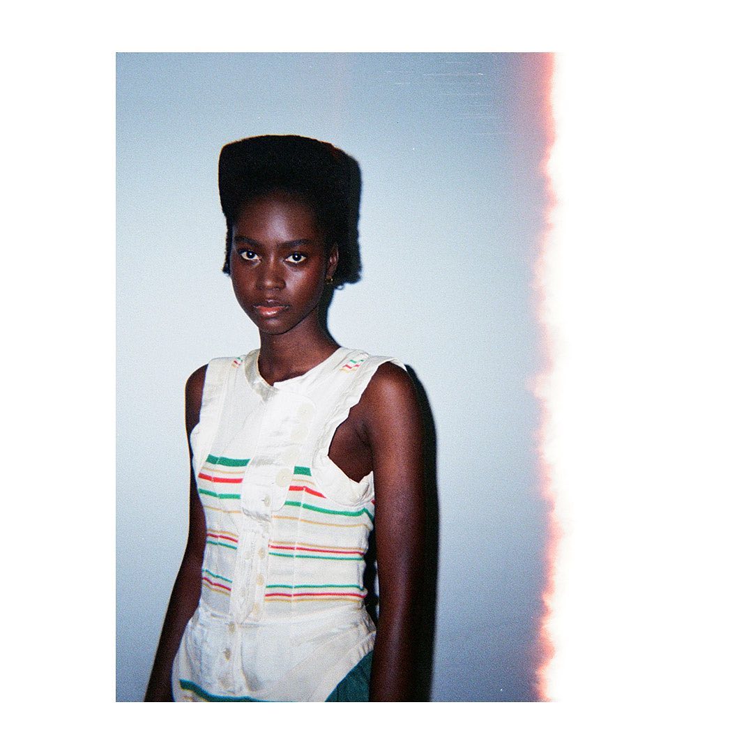 Portrait of an African woman in a tank top against a pale blue background, shot in a photo studio, with a vintage effect.