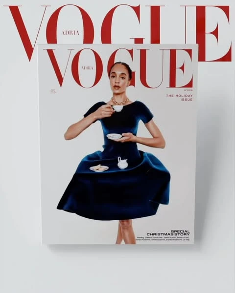 Vogue magazine cover featuring a woman in a blue dress holding a teacup, with red Vogue masthead visible on the cover and in the background.