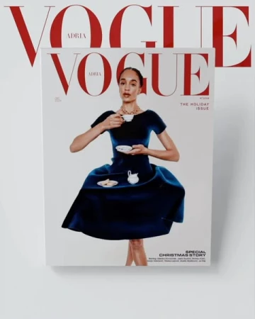 Vogue magazine cover featuring a woman in a blue dress holding a teacup, with red Vogue masthead visible on the cover and in the background.
