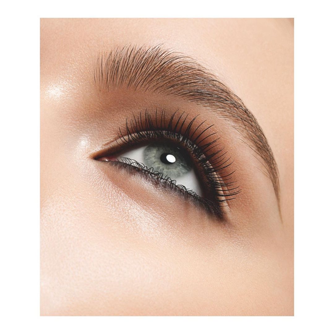 Close-up studio shot of a woman's eye showcasing black eyeliner, dark lashes, a defined eyebrow, and light skin tones in beauty advertising.