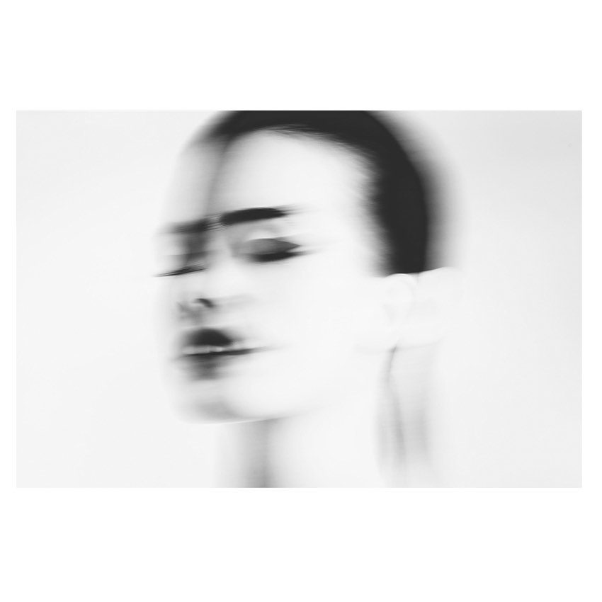 Abstract black and white portrait of a woman with blurry features, minimalist composition, emphasizing light and shadow.