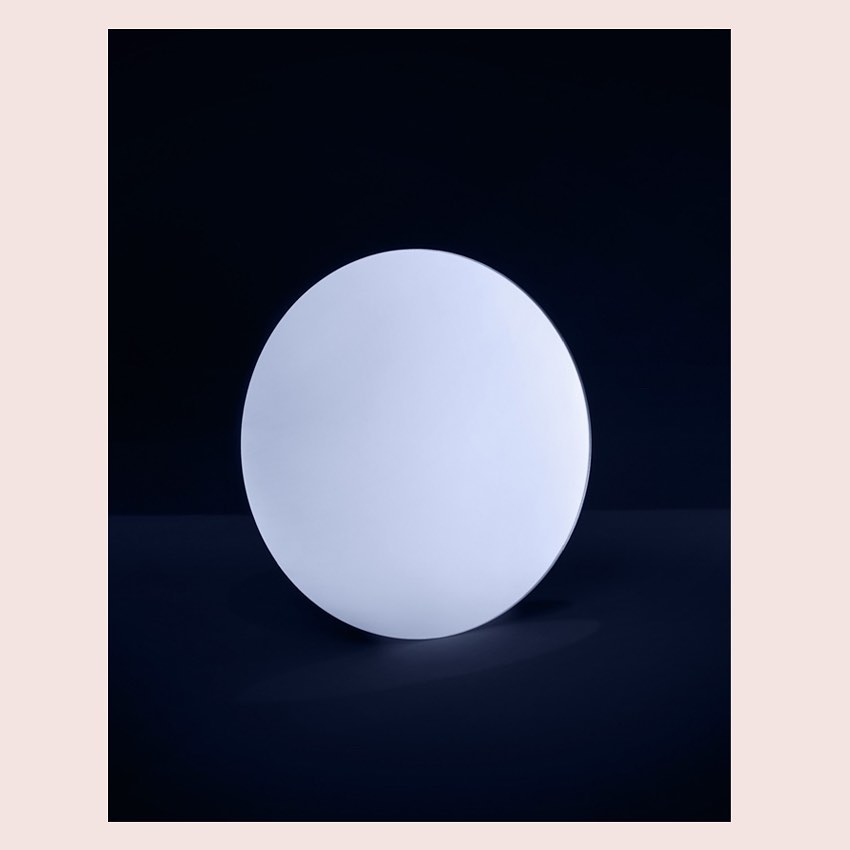Minimalist product shot of a glowing white spherical lamp against a dark backdrop, highlighting its smooth texture and simple design.