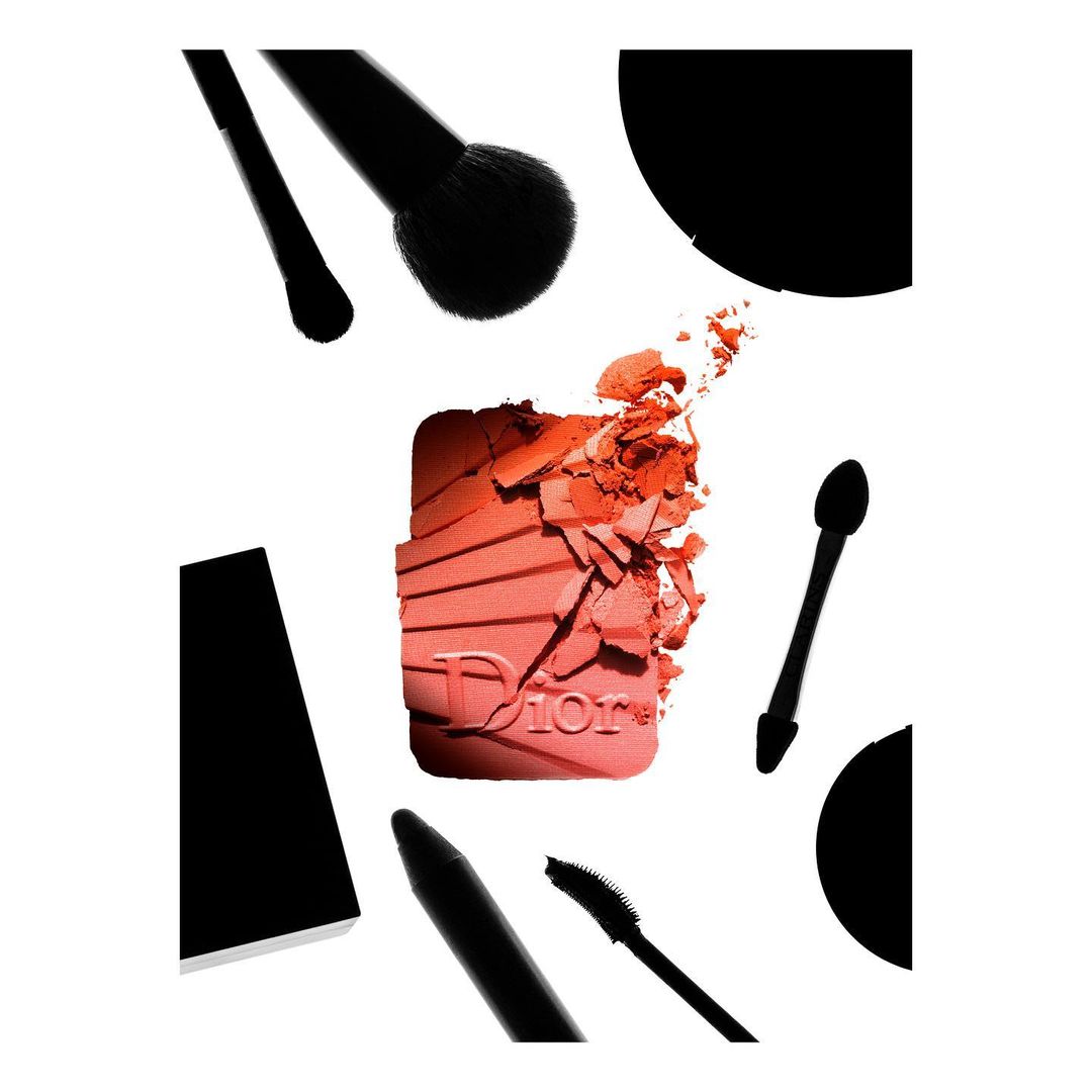 Product shot of a coral-colored blush palette by Dior with make-up brushes and applicators on a white background for beauty advertising.
