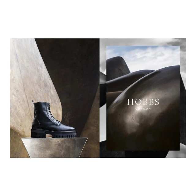 Black leather lace-up boot on geometric pedestal, minimalist fashion product shot with Hobbs London branding in the background.