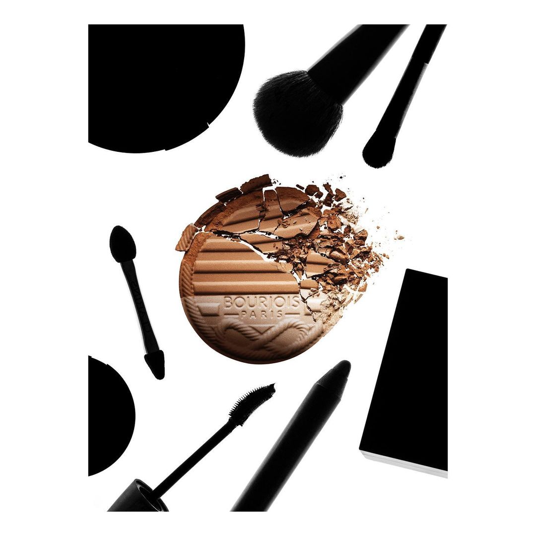 Cosmetic bronzer palette and brushes on a white backdrop, showcasing makeup tools and product with a focus on texture and color.