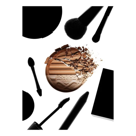 Cosmetic bronzer palette and brushes on a white backdrop, showcasing makeup tools and product with a focus on texture and color.