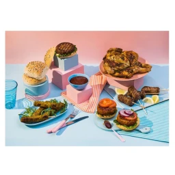 Assorted grilled meats, burgers, and skewers arranged on pastel-colored geometric blocks and plates with a pink and blue background