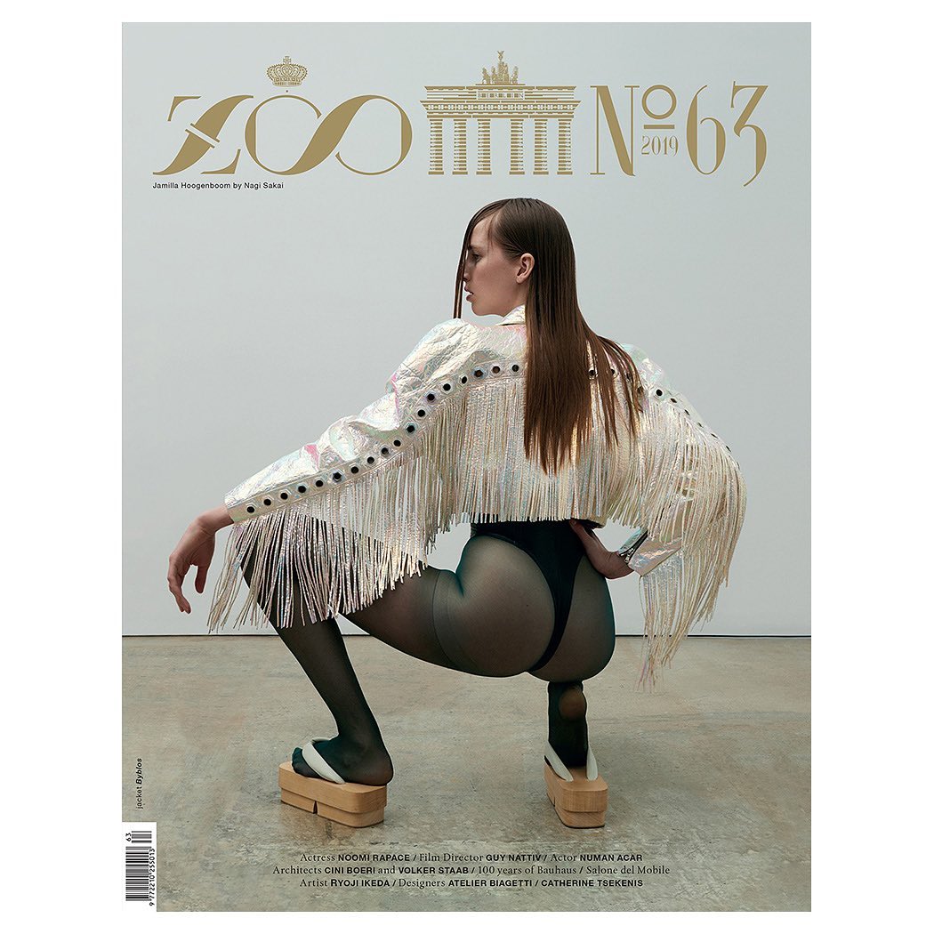 Magazine cover featuring a woman in a fringe jacket and platform shoes, crouching against a neutral background.