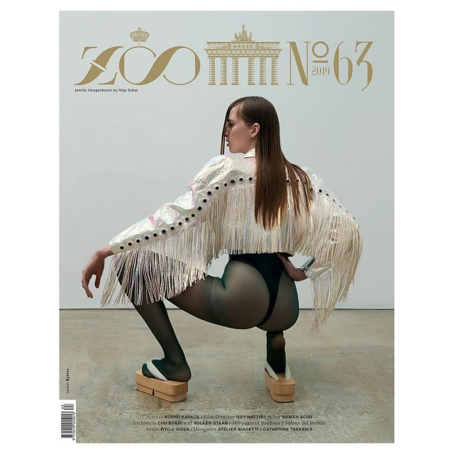 Magazine cover featuring a woman in a fringe jacket and platform shoes, crouching against a neutral background.