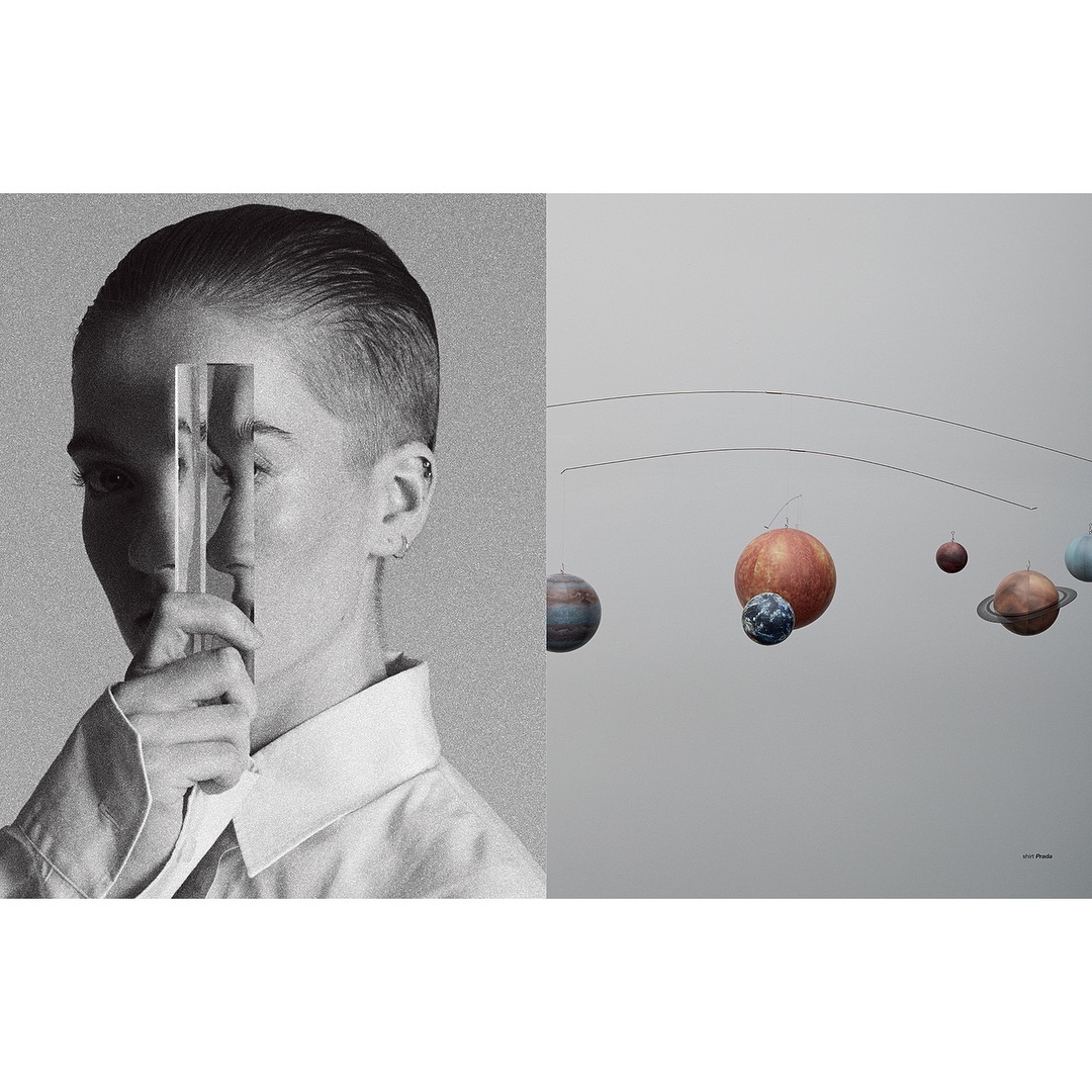Conceptual still life: person holding a glass prism in black and white next to a mobile of planets on a light gray backdrop.