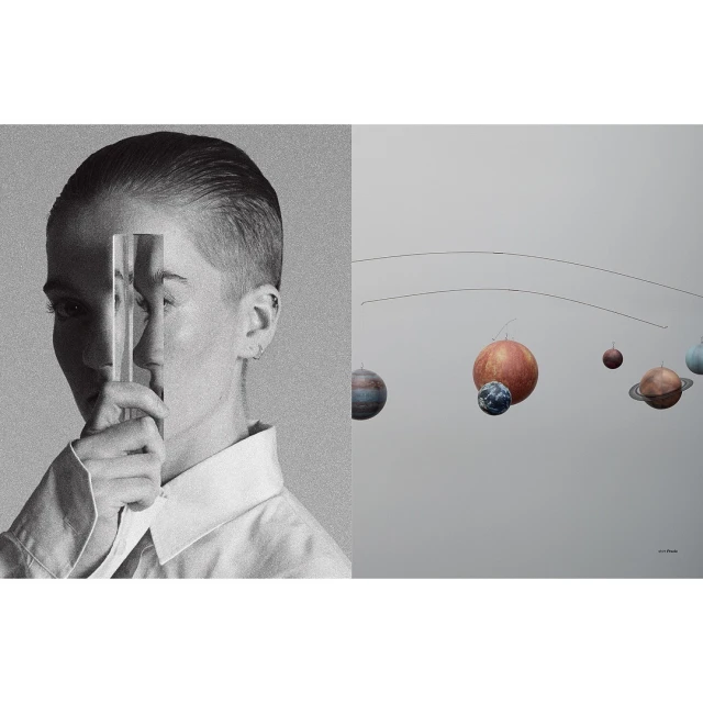 Conceptual still life: person holding a glass prism in black and white next to a mobile of planets on a light gray backdrop.