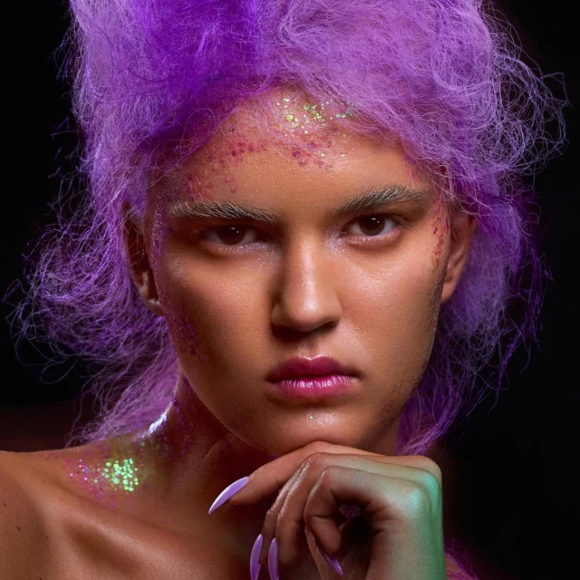 Close-up portrait of a person with purple hair and glitter makeup in a studio setting with a dark background. Beauty and fashion.