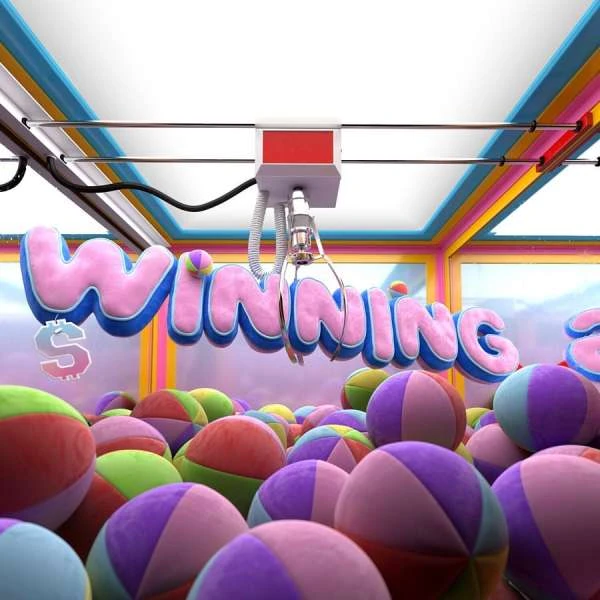 Close-up of a claw crane game filled with colorful beach balls and text 'Winning' in pink and blue, symbolizing games and prizes.