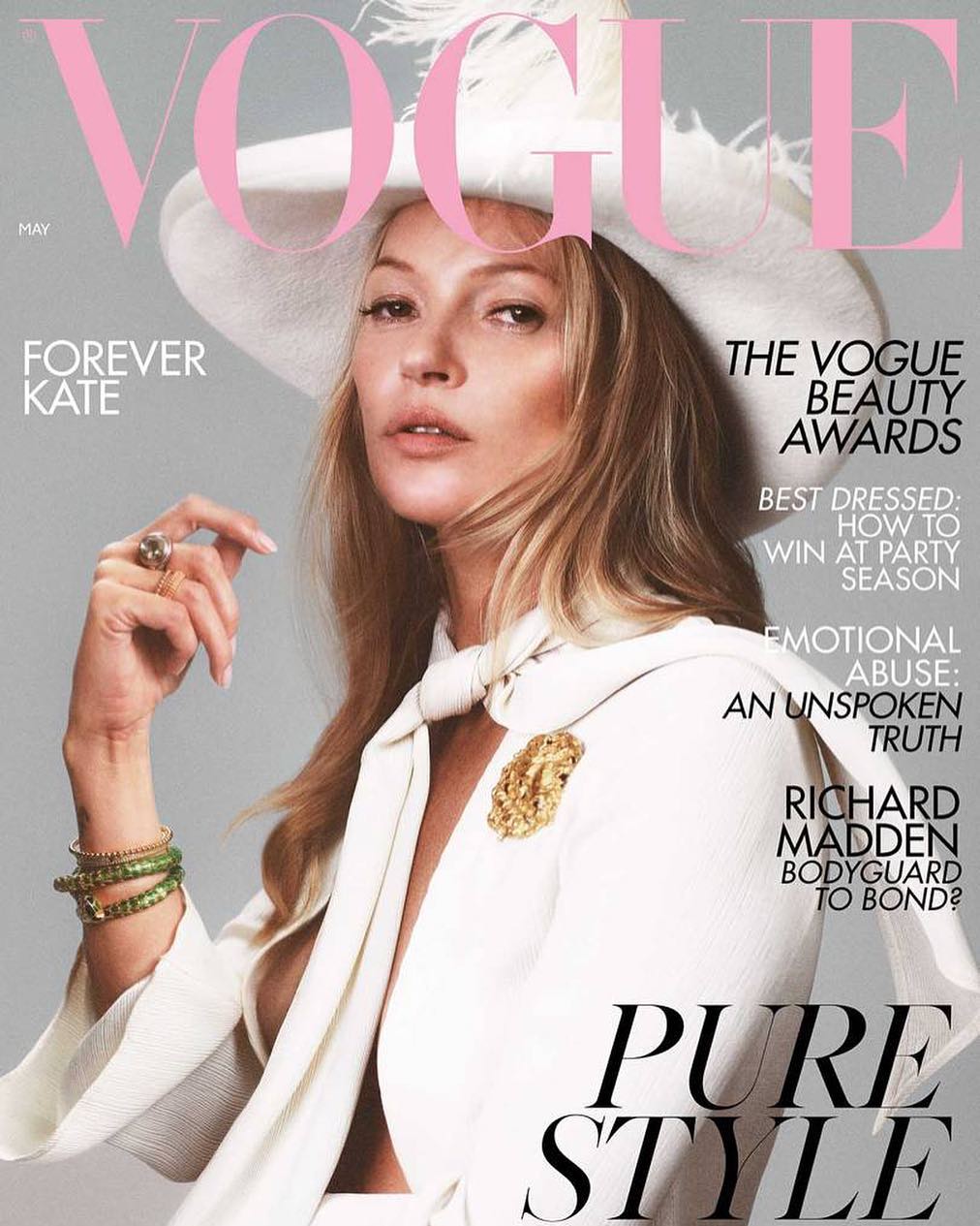 Kate Moss on the cover of Vogue magazine, wearing a white hat and outfit with green bracelets, in a head and shoulders shot.