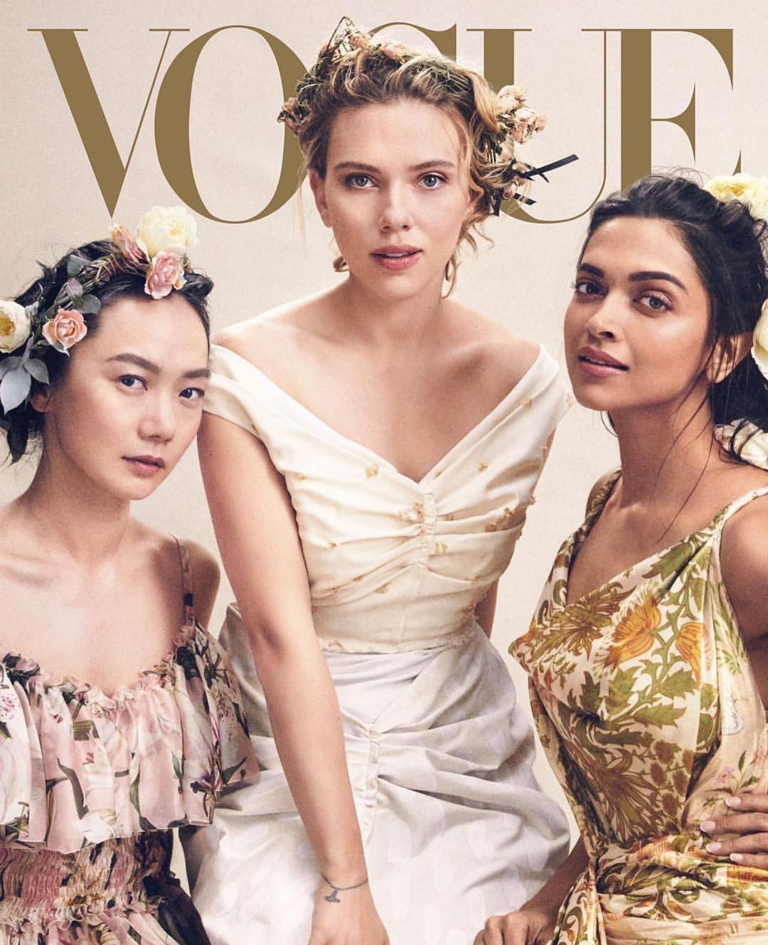 Vogue cover featuring three women with floral headpieces. The woman in the center wears an off-the-shoulder white dress; the women on either side wear floral print dresses.