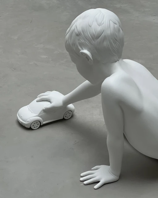 Monochromatic art still life of a child statue playing with a car toy in a modern setting, shot with neutral, soft lighting.