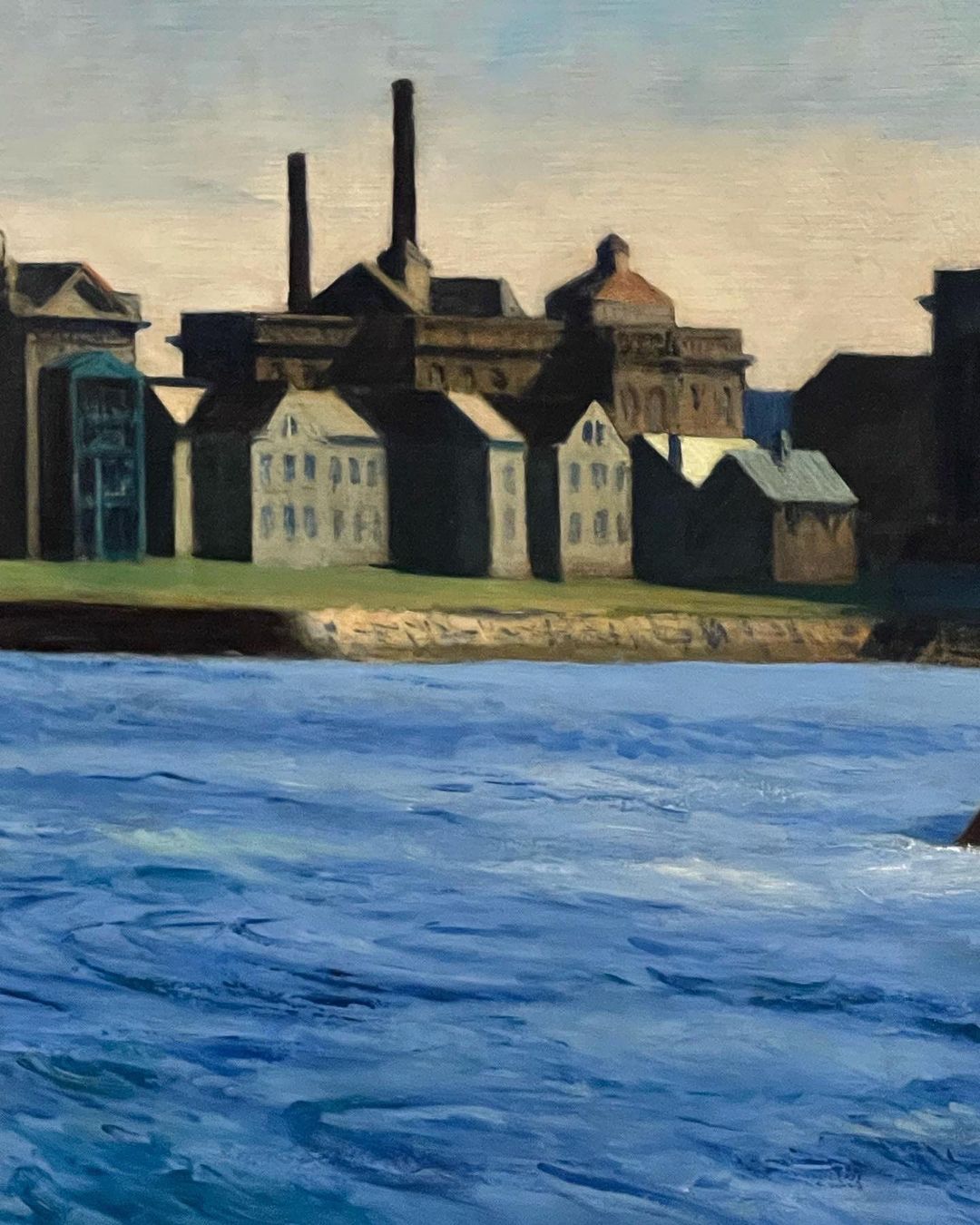 Oil painting of an industrial waterfront features factory buildings, chimneys, and warehouses along a river under a blue and white sky.