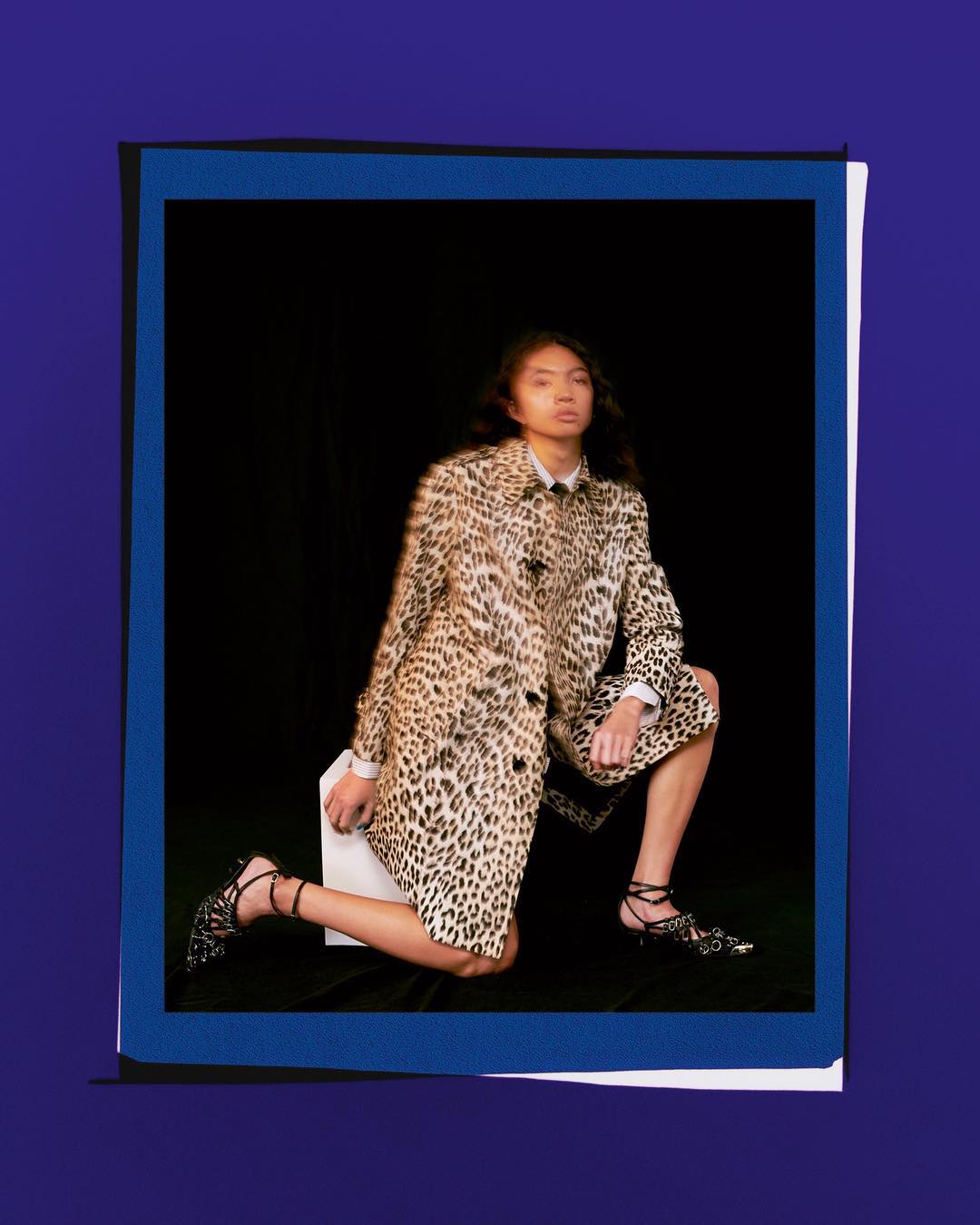 Woman in leopard-print coat poses in a blue-framed photo, creating a fashion editorial look with dark backdrop and stylish outfit.