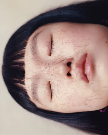 Close-up portrait of a woman with closed eyes and loose hair strands scattered across her face by photographer Mat+kat.