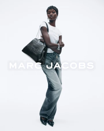 Model in white t-shirt and grey jeans wearing a black leather shoulder bag against a white background with text
