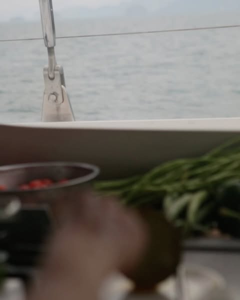 View of the ocean from a sailboat featuring fresh produce including tomatoes, green beans, and coconuts.