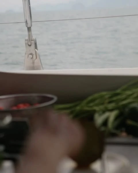 View of the ocean from a sailboat featuring fresh produce including tomatoes, green beans, and coconuts.