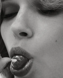 Extreme close-up monochrome portrait of a woman holding a small round object near her lips by photographer Hong Jang Huyn.