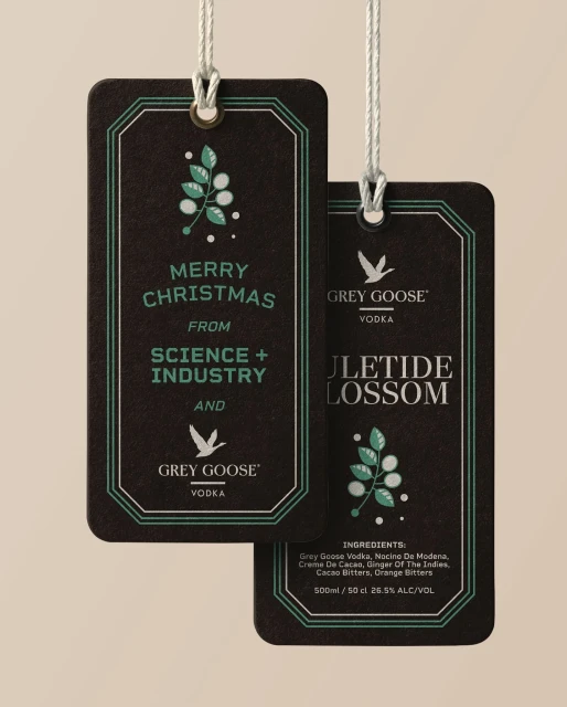 Grey Goose Vodka holiday gift tag featuring a festive holiday greeting and brand logo on a dark background with mint-green accents.