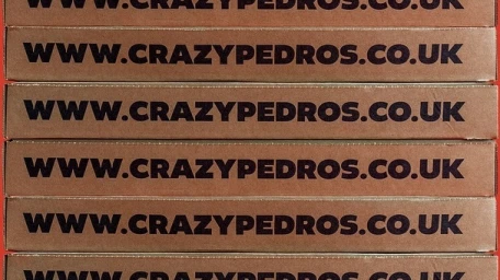 Stacked brown cardboard pizza boxes featuring printed website text across the front