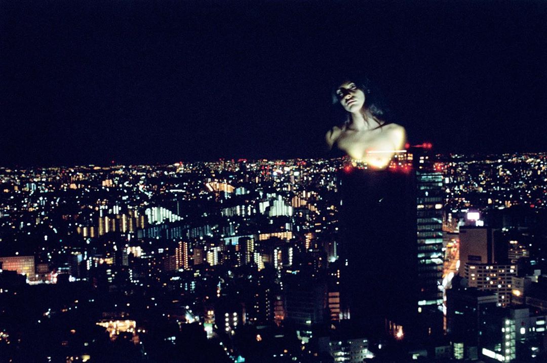 Night cityscape with an ethereal adult female figure merged with the city lights, creating a surreal urban portrait.