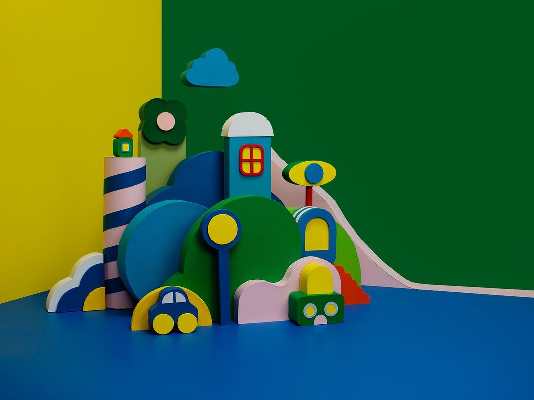Abstract art: Colorful wooden block city scene with toy car and cloud against yellow and green background, vivid and whimsical.