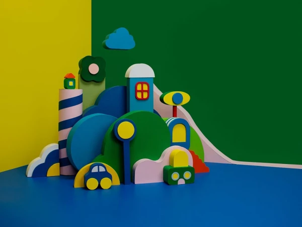 Abstract art: Colorful wooden block city scene with toy car and cloud against yellow and green background, vivid and whimsical.