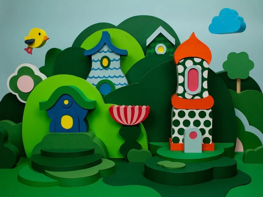 Paper art scene of colourful toy houses and trees on green hills under a blue sky, creating a whimsical and playful landscape.