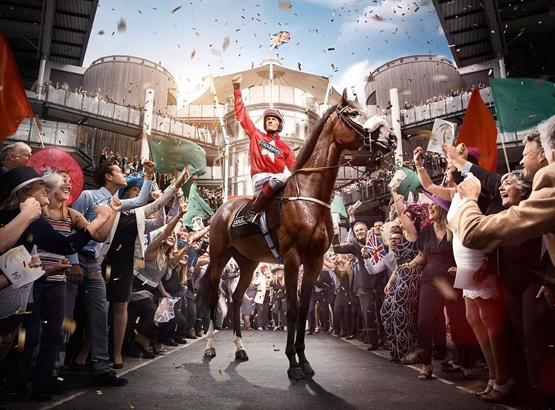 Jockey on horseback celebrates victory with cheering crowd and confetti at daytime horse race event under open stadium roof.
