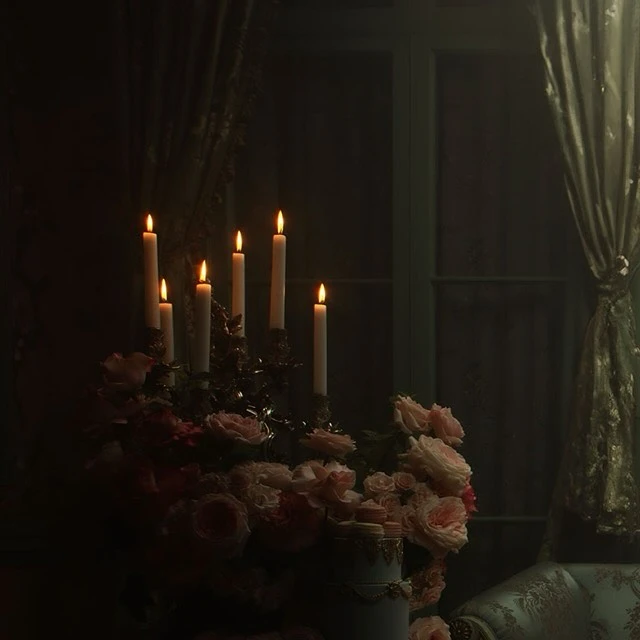 A dimly lit image of a candelabra with lit candles on a table with flowers and an antique chair in a dark interior setting.