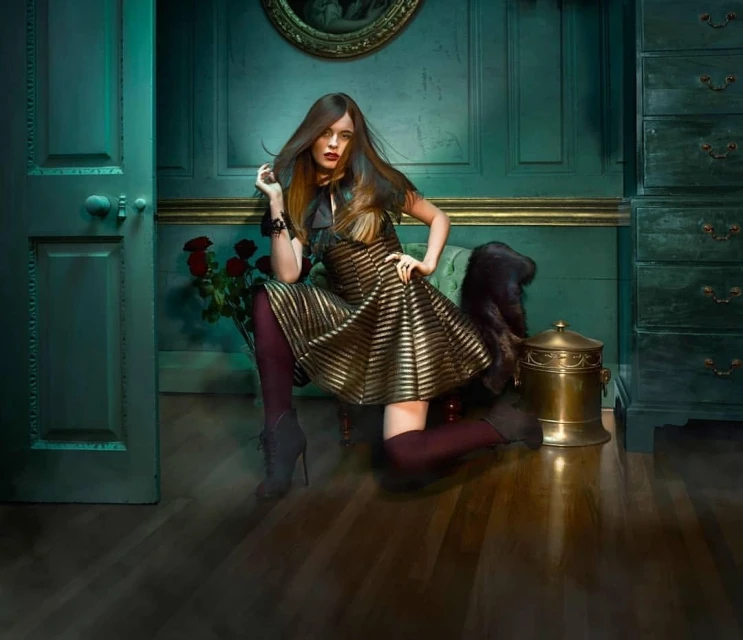 A fashionable woman in a gold-striped dress poses in an elegant interior with dark green walls, wooden floors, a wardrobe, and roses.