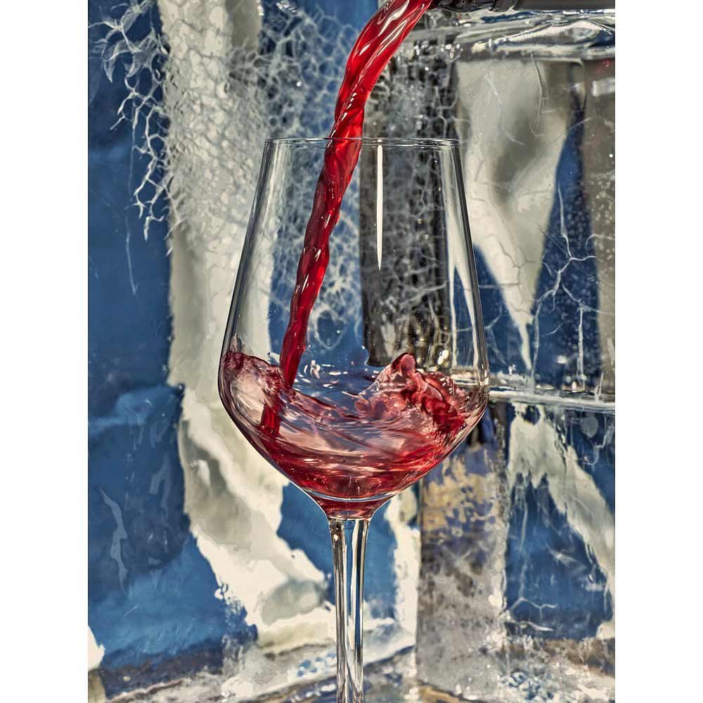 Red wine being poured into a clear glass stemware against an icy textured blue and white background.