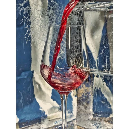 Red wine being poured into a clear glass stemware against an icy textured blue and white background.