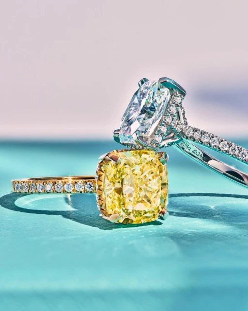 Close-up of two diamond rings, one with a yellow diamond and gold band, the other with a white diamond and platinum band.