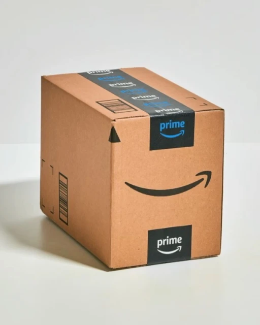 Brown cardboard box from Amazon Prime with the Prime logo and branding, sitting on a white surface in a studio setting.