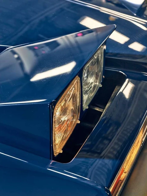 Close-up of a classic blue car headlight, showcasing its sharp design and reflective surface in bright light, automotive photography.
