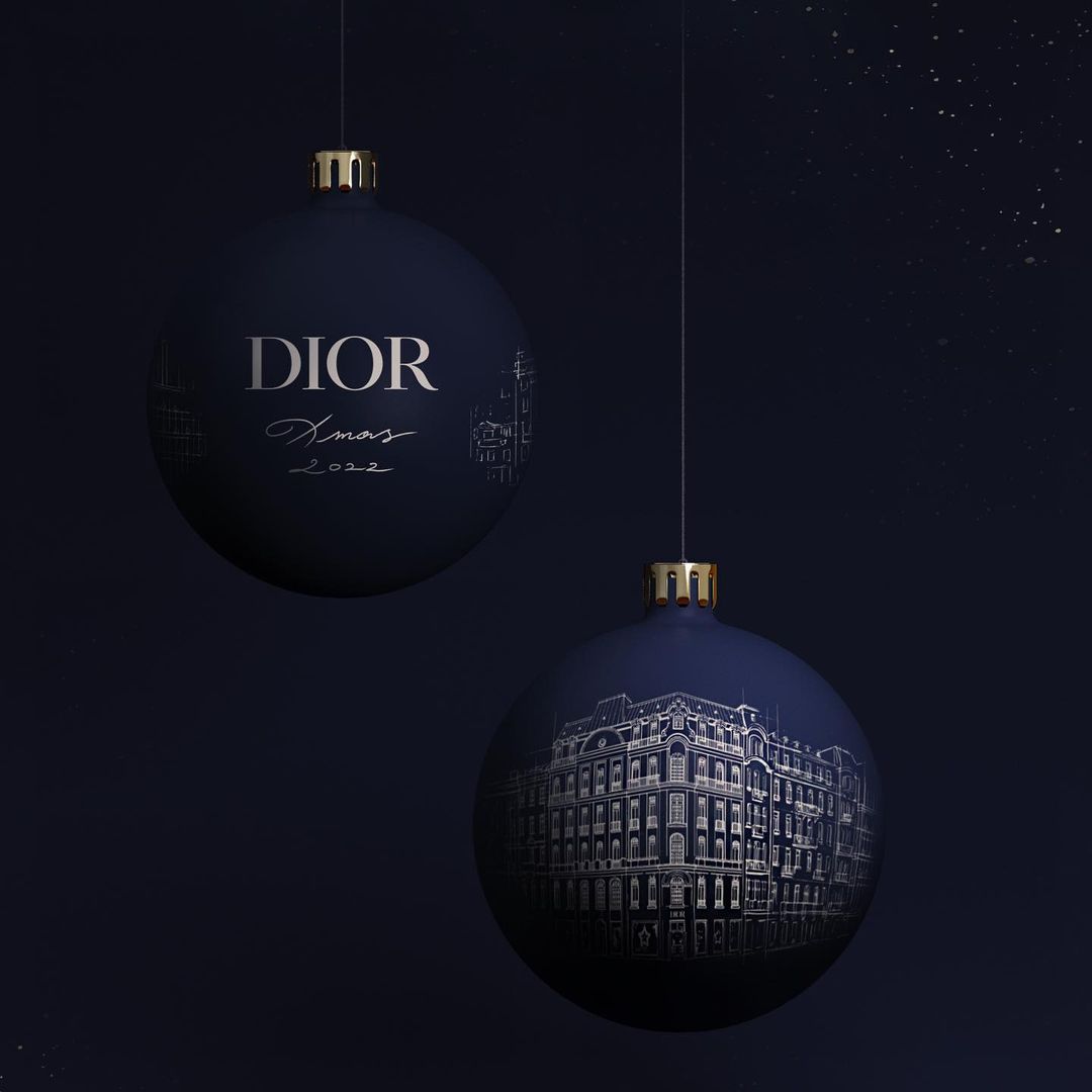 Elegant navy Christmas ornament spheres, suspended against a dark background, display building illustrations and the Dior logo, festive and stylish.