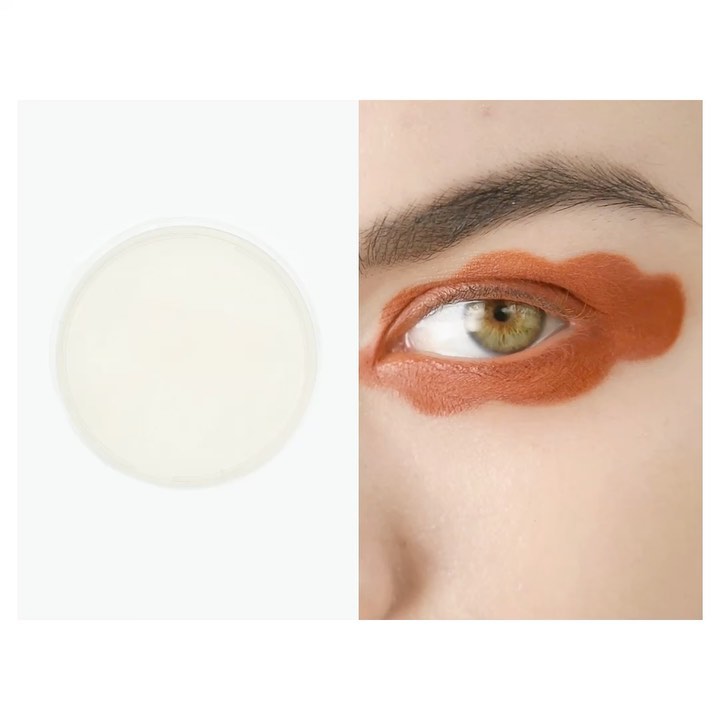 Close-up of a person's face showcasing creative orange eyeshadow in a cloud-like pattern, next to a skincare product on a white background.