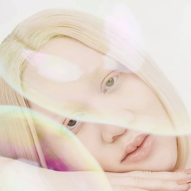 Portrait of a fair-skinned woman with albinism laying down, blonde hair, light eye makeup, with transparent bubbles in a light background.