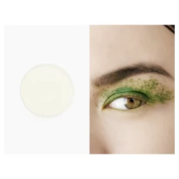 Close-up of a person's eye with green powder eyeshadow and a circular jar of white cream on white background