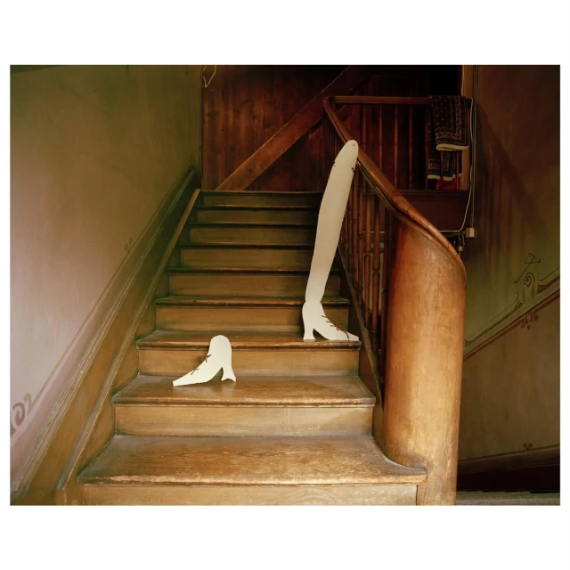 Whimsical art photo of abandoned white shoe forms on wooden stairs with dark wood banister in a traditional residential building.