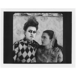 Black and white portrait of two women, one with dramatic clown makeup and harlequin patterned top, by photographer Elena Rendina.