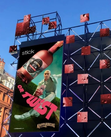Advertisement for Kopparberg Gin featuring a man holding a bottle in front of a green hedge, displayed on a large billboard.