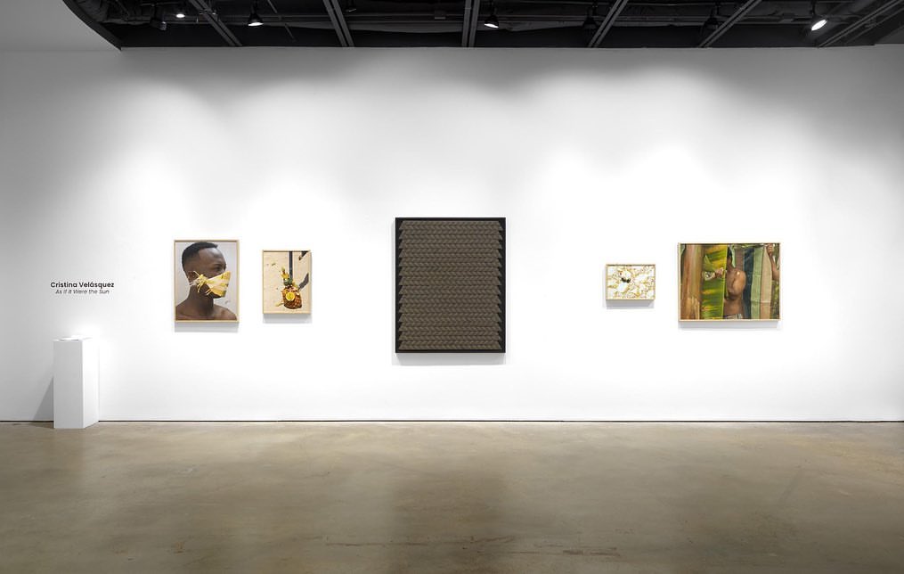 Art gallery featuring five framed artworks with portraits and abstract designs displayed on a white wall under spotlighting, creating a cultural ambiance.