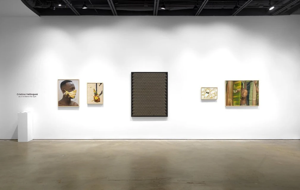 Art gallery featuring five framed artworks with portraits and abstract designs displayed on a white wall under spotlighting, creating a cultural ambiance.